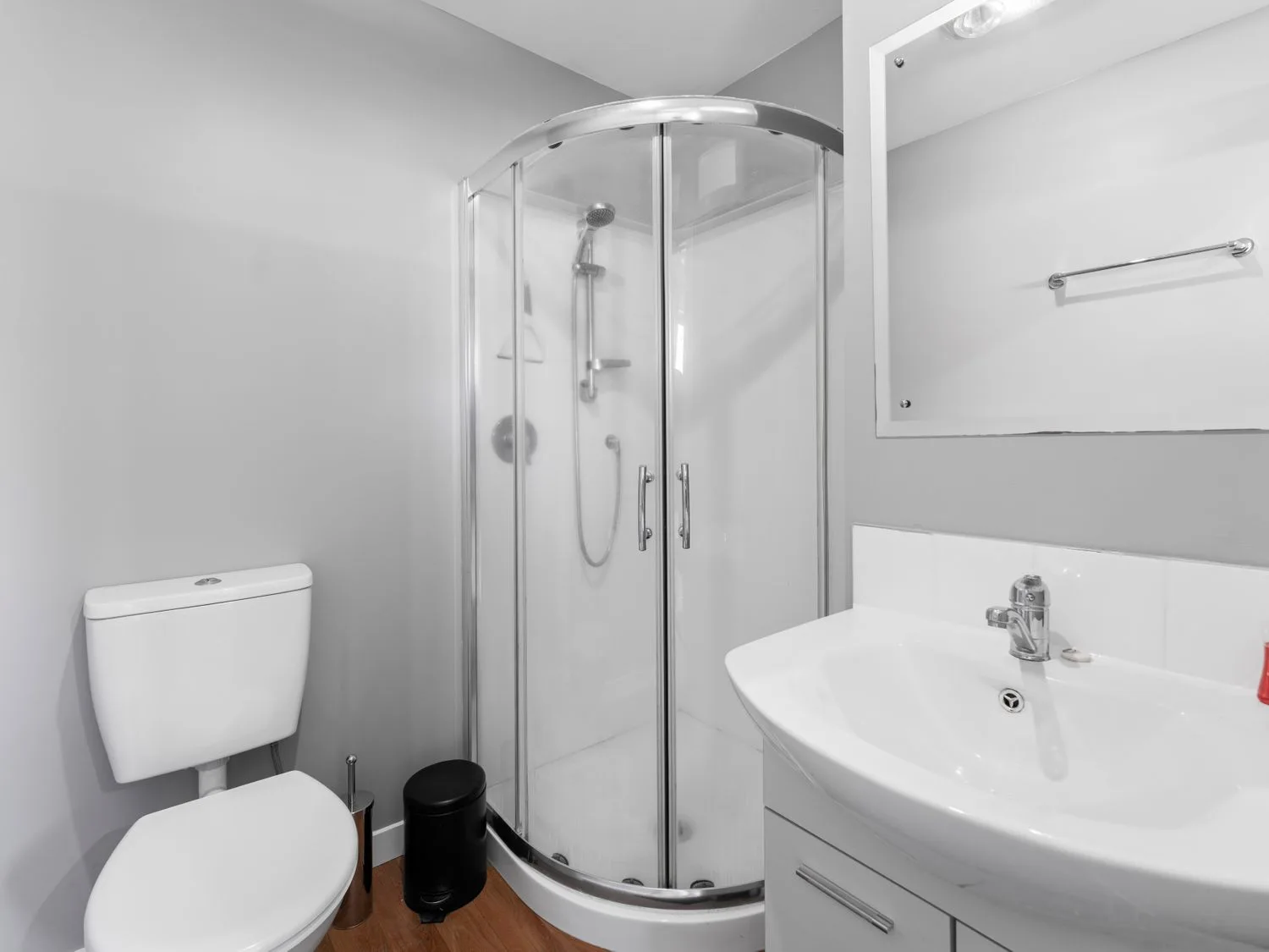 A bathroom with a toilet, shower, and sink.