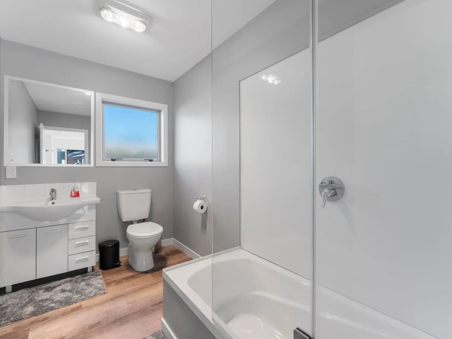 A bright bathroom with a bathtub, shower, vanity, and window.