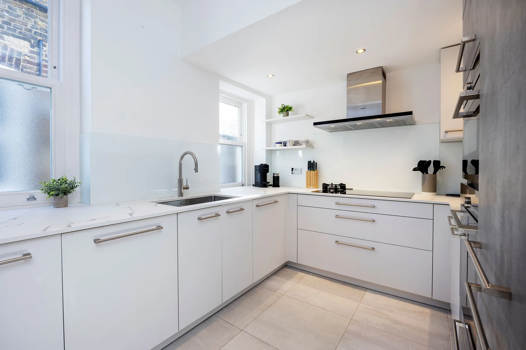 Una cocina blanca y luminosa con espacio de trabajo en la encimera y electrodomésticos de acero inoxidable.