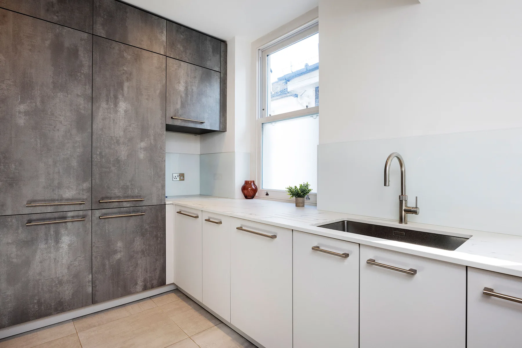 Una cocina moderna y luminosa con gabinetes blancos y una encimera larga.