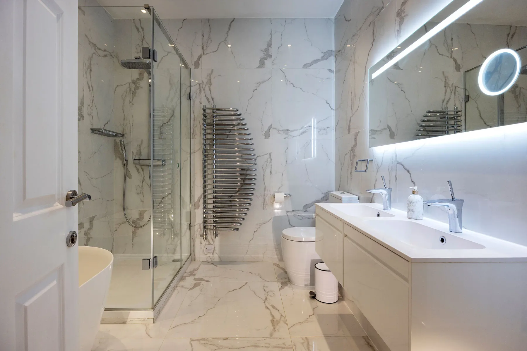 Un baño luminoso con una ducha de cristal y un mueble de lavabo alargado.