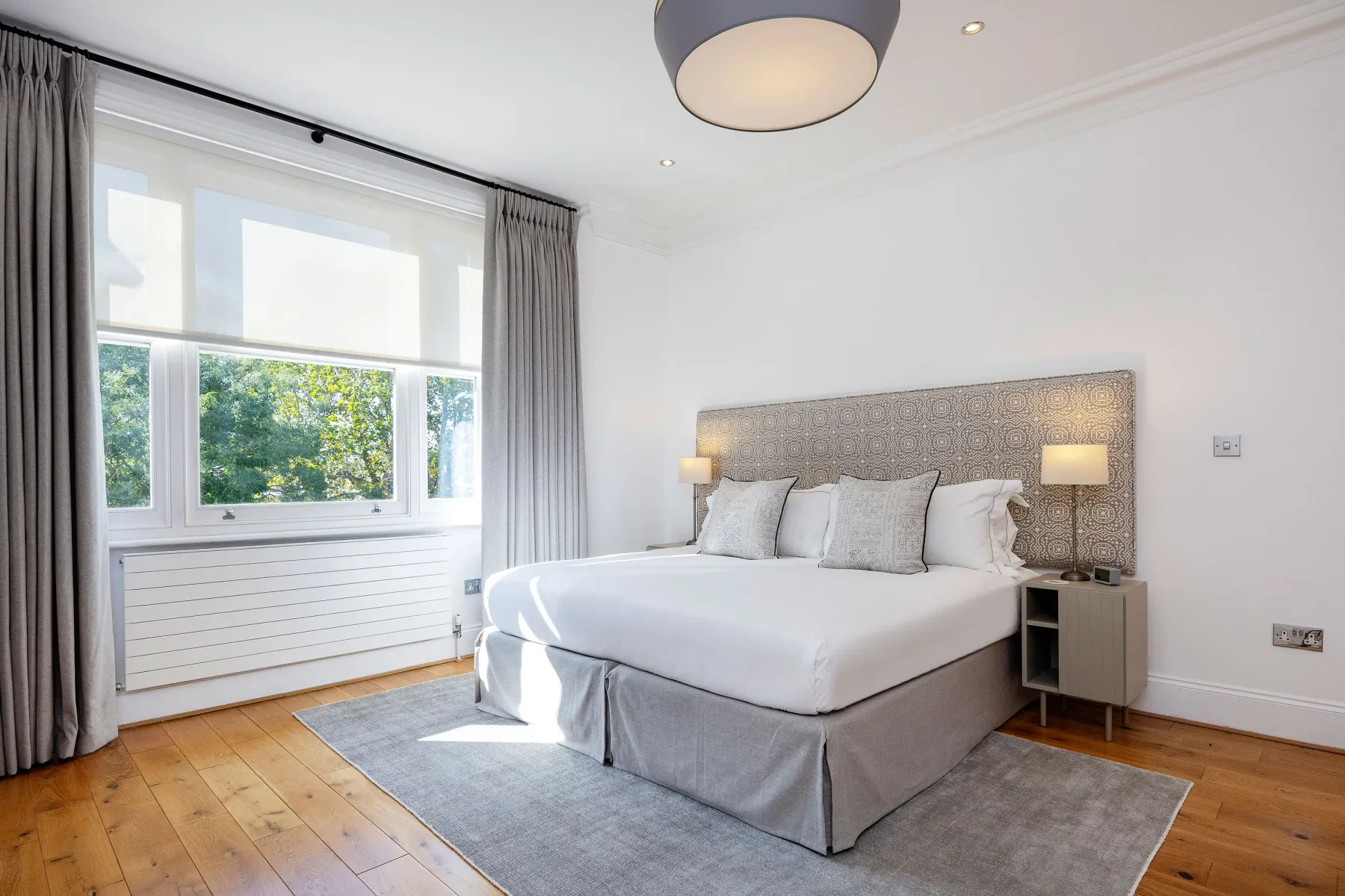 Un dormitorio luminoso con una cama grande junto a una ventana.