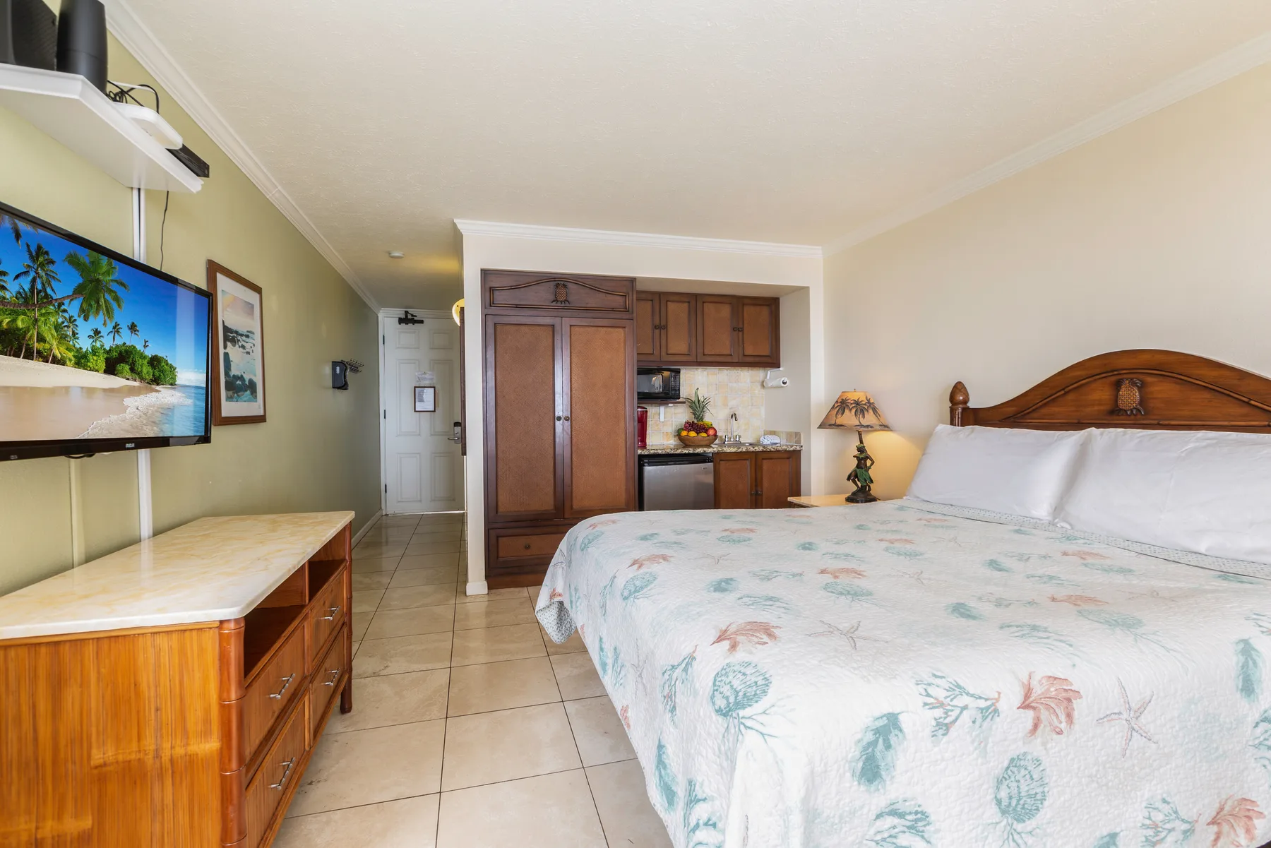 Un dormitorio con una cama grande y una pequeña cocina junto a la pared del fondo.
