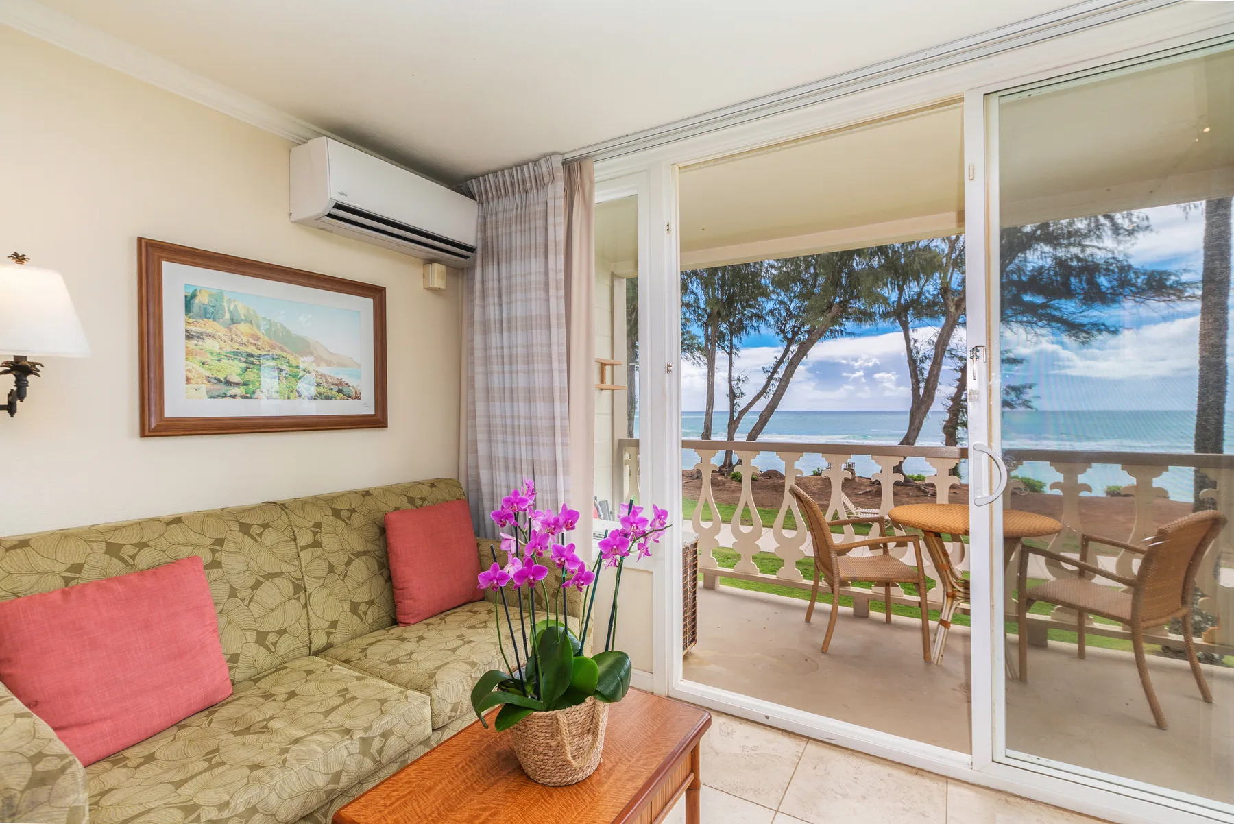 Una sala de estar da a un balcón con asientos y vistas al mar.