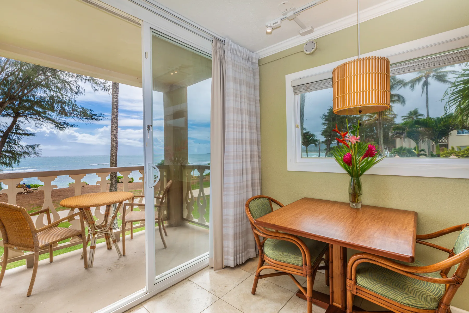 Un comedor con una mesa de madera y sillas junto a puertas de vidrio con vistas al mar.