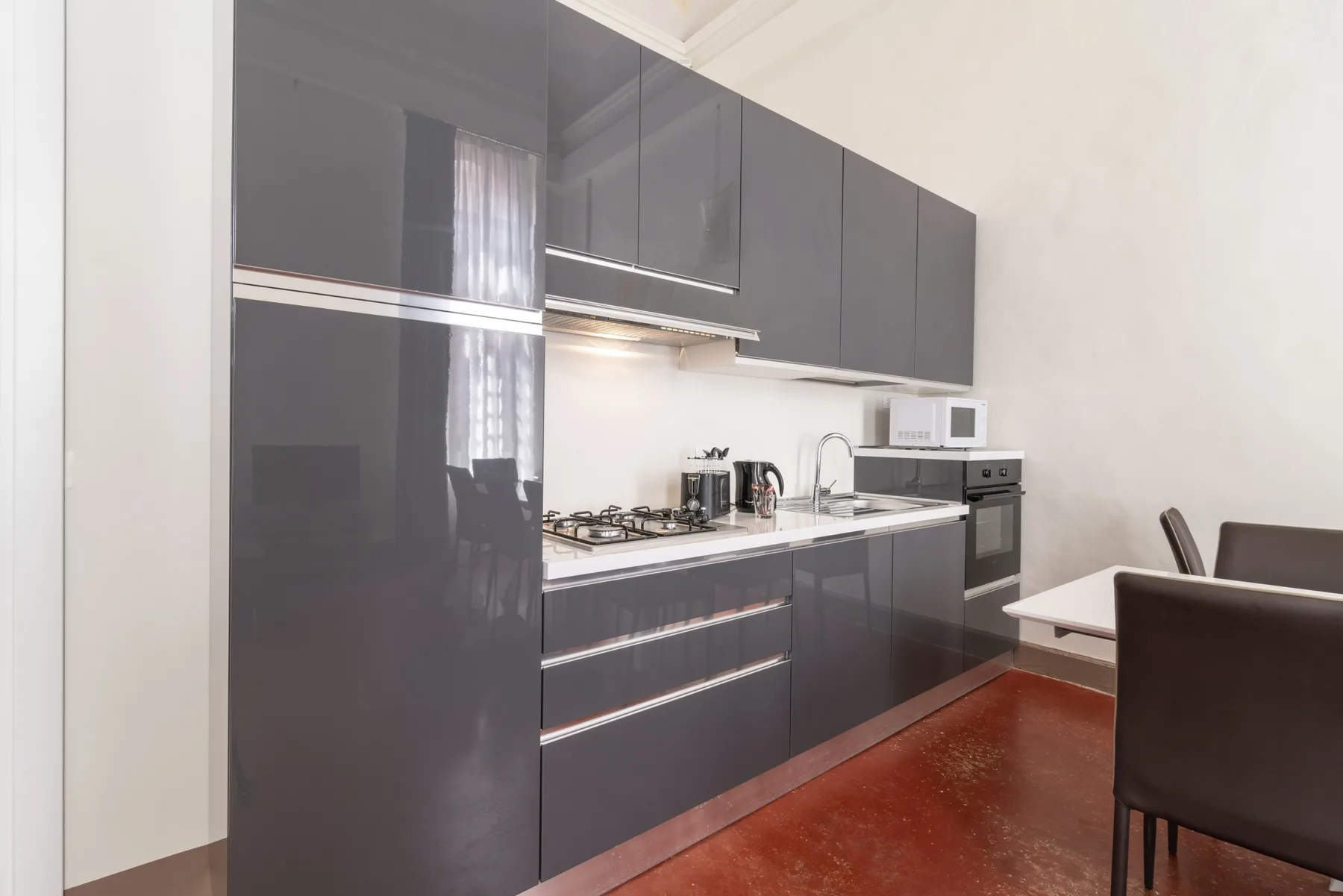 Una cocina moderna con gabinetes oscuros, encimera y electrodomésticos integrados.