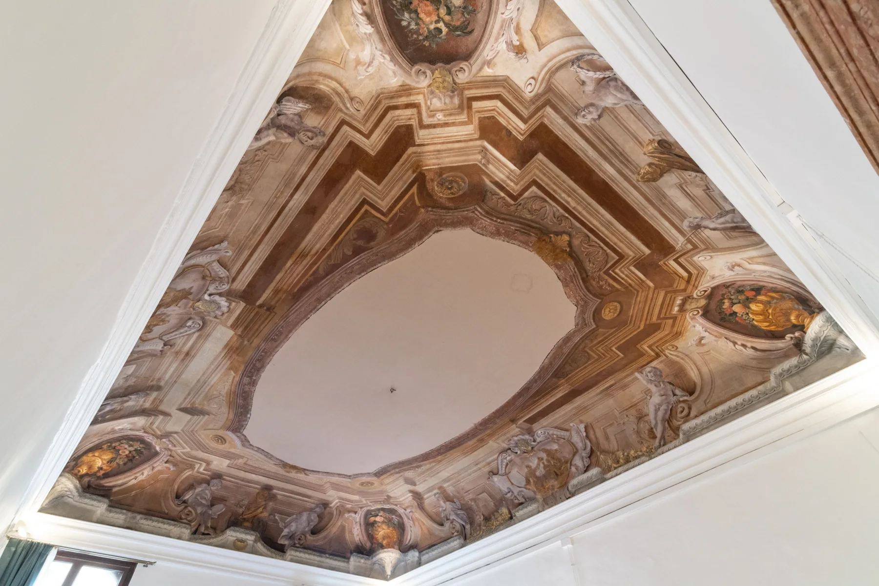 Un techo pintado ornamentado presenta figuras decorativas y un gran panel central.