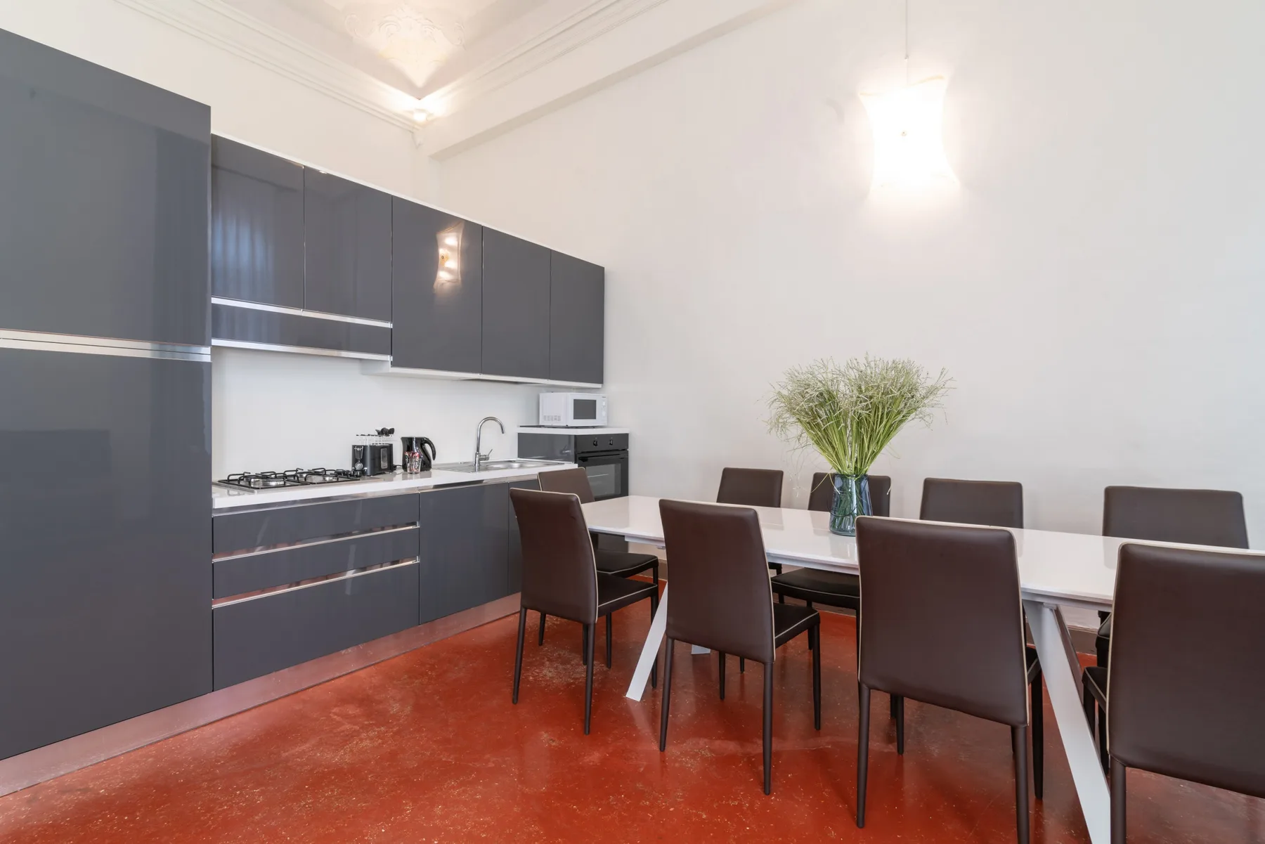 Un comedor con una mesa larga y asientos oscuros junto a una cocina moderna.