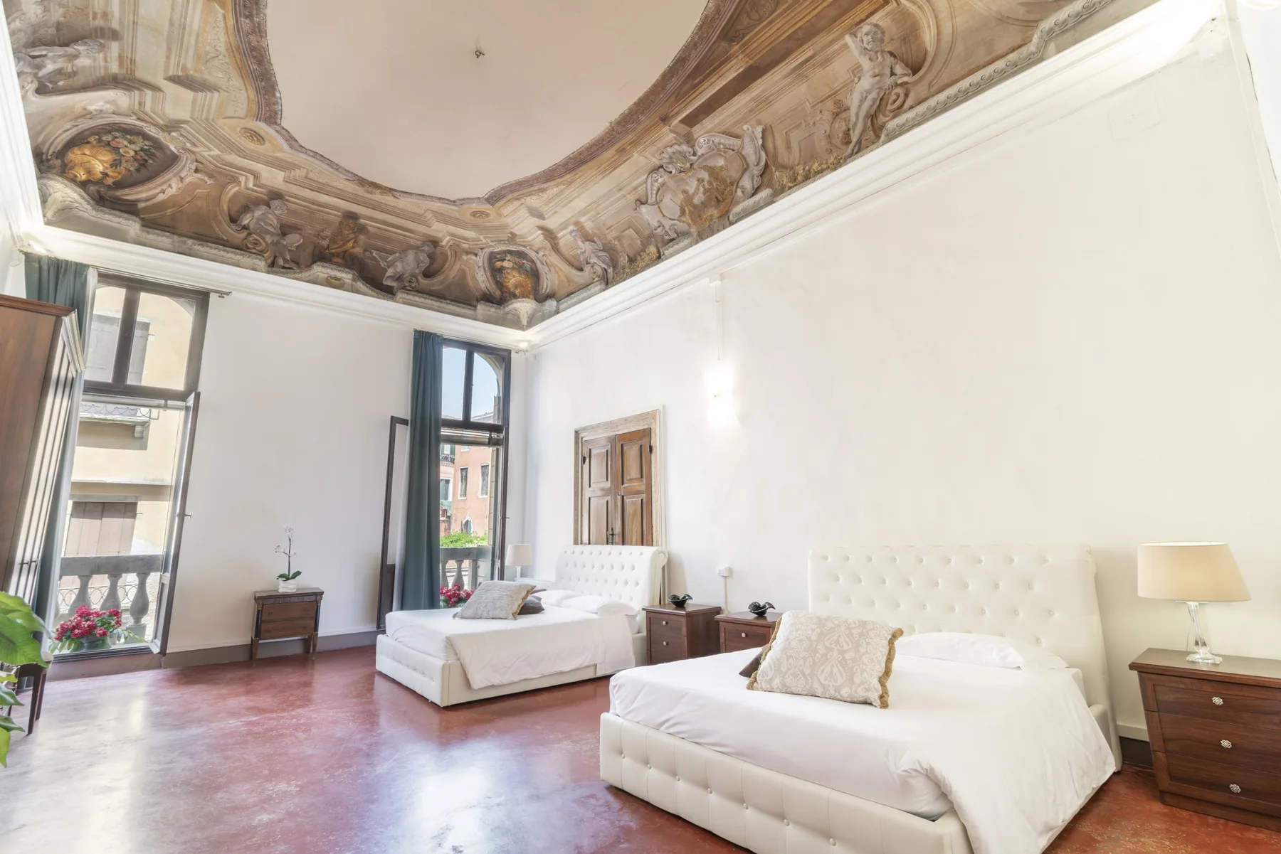 Un dormitorio luminoso con dos camas y un techo pintado ornamentado.