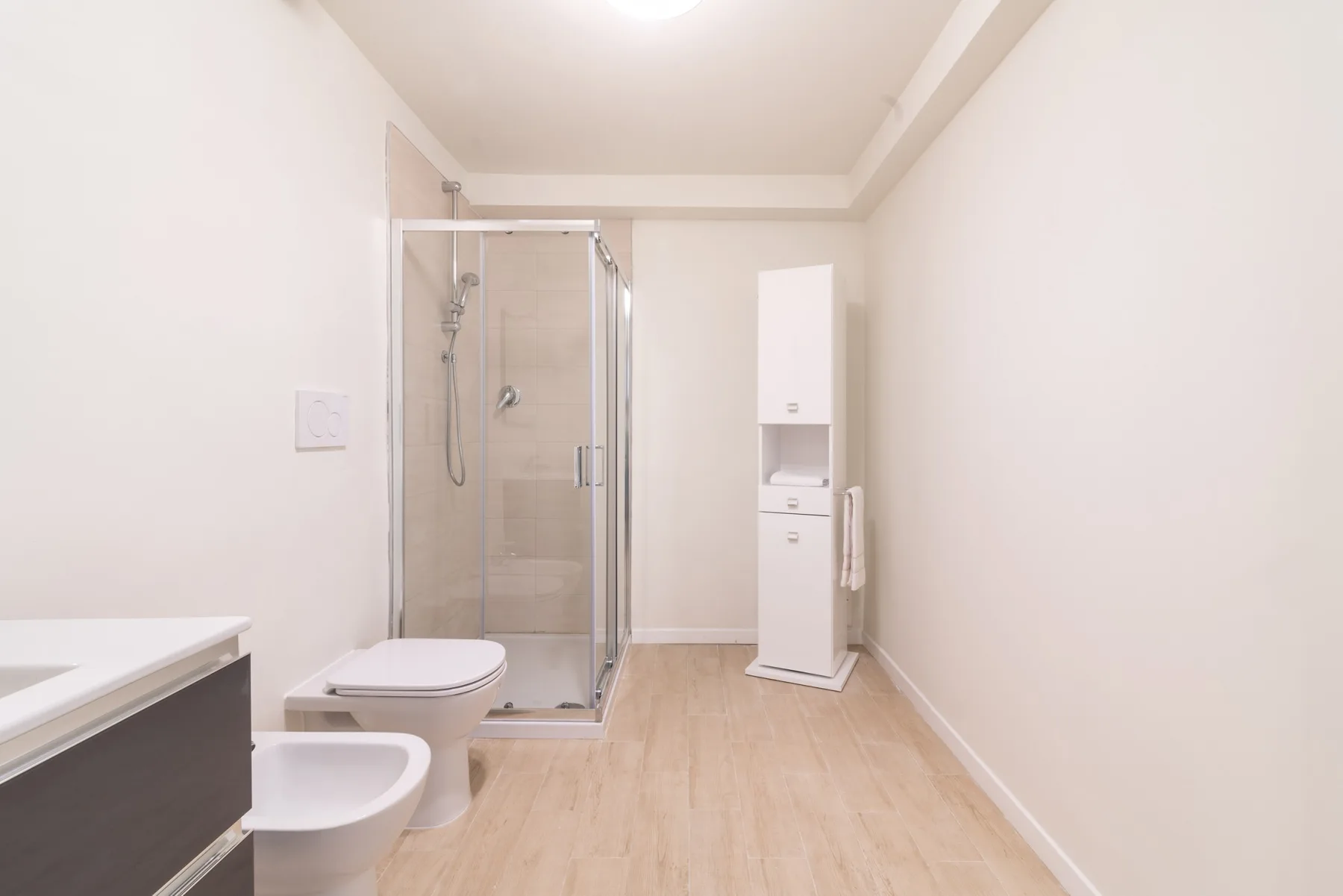 Un baño luminoso con ducha de vidrio, inodoro y lavabo.
