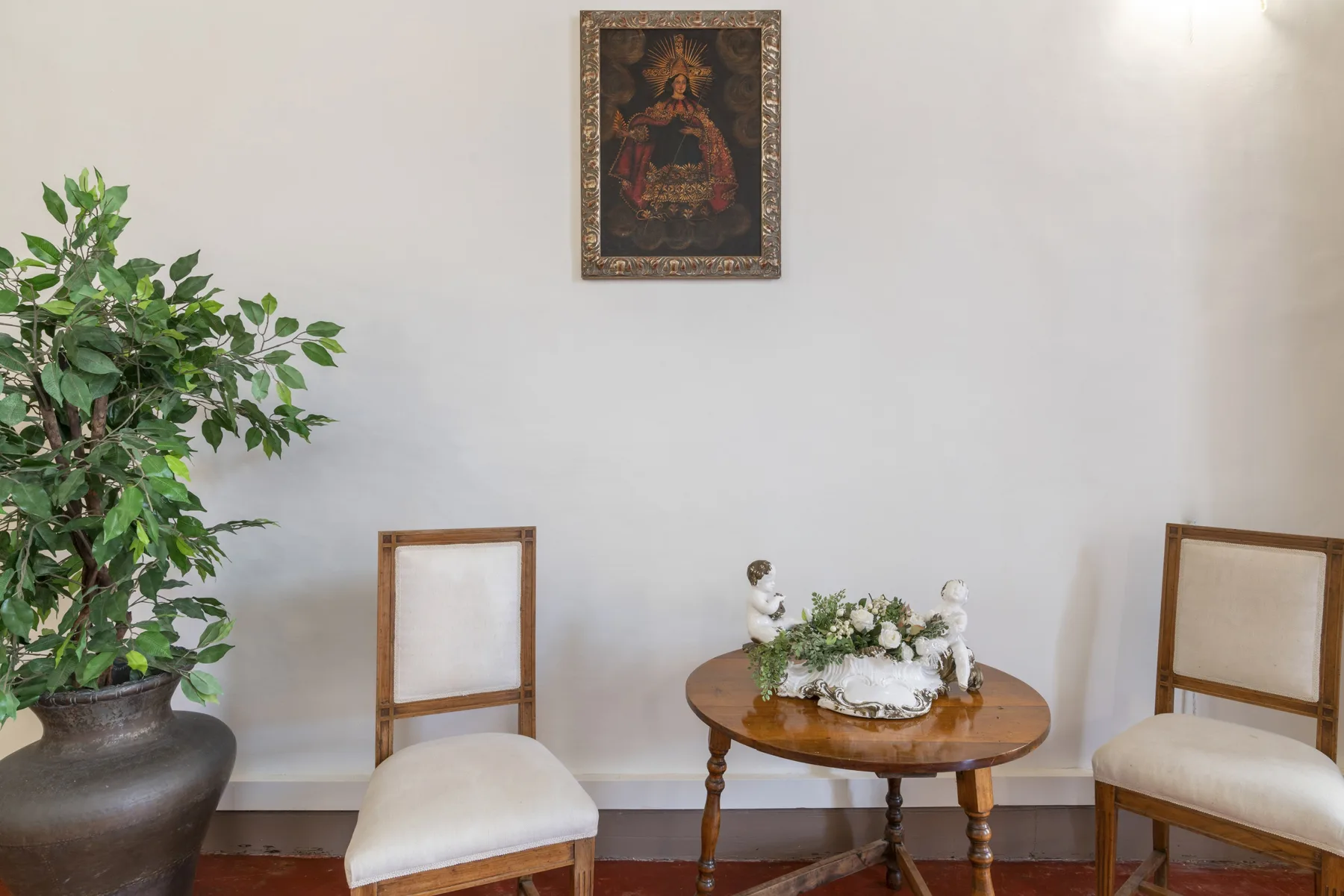 Una zona de estar con dos sillas y una mesa redonda pequeña bajo un cuadro.