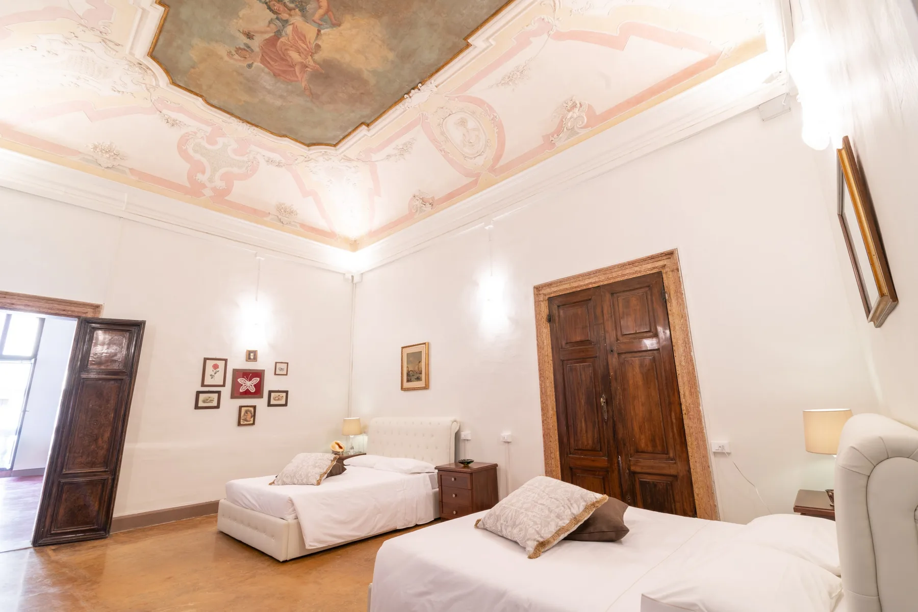 Un dormitorio con dos camas, puertas de madera oscura y un techo decorado.