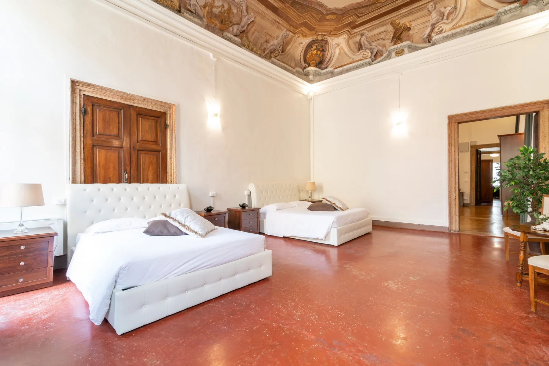Un dormitorio con dos camas bajo un techo pintado ornamentado.