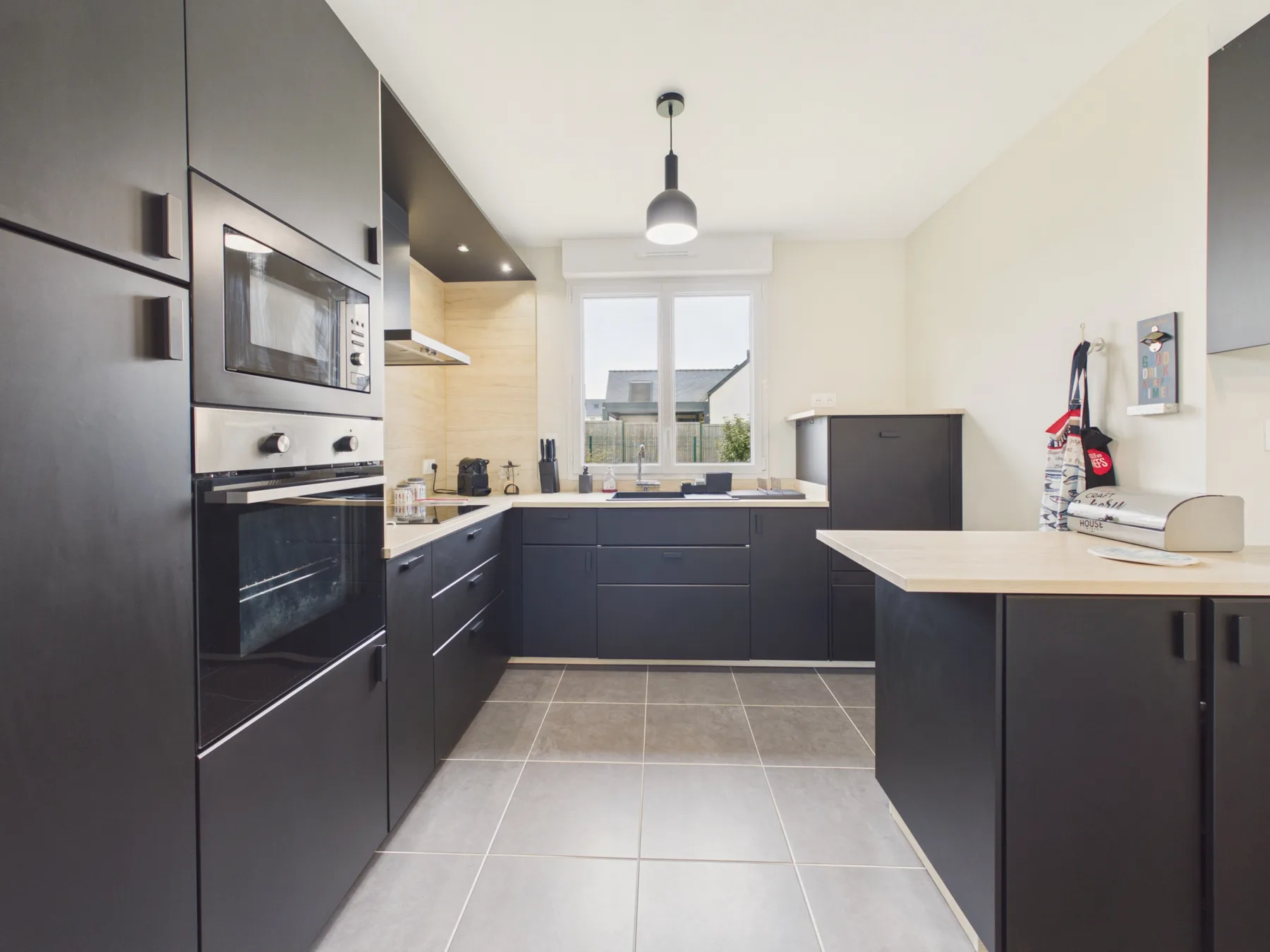 A modern kitchen with dark cabinets, a central island, and a window.