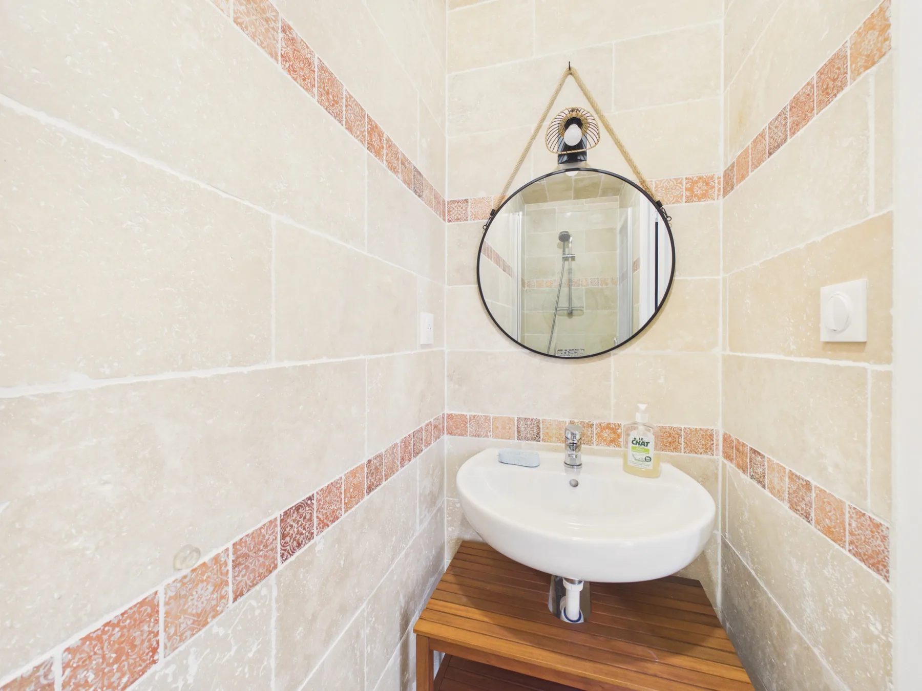 A compact bathroom with a wall-mounted sink and round mirror.