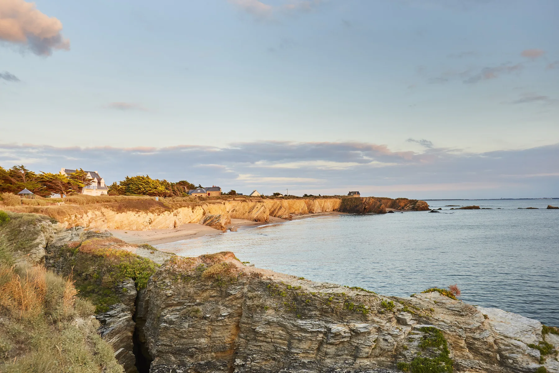 Coastal shoreline with rocky cliffs beside calm water.