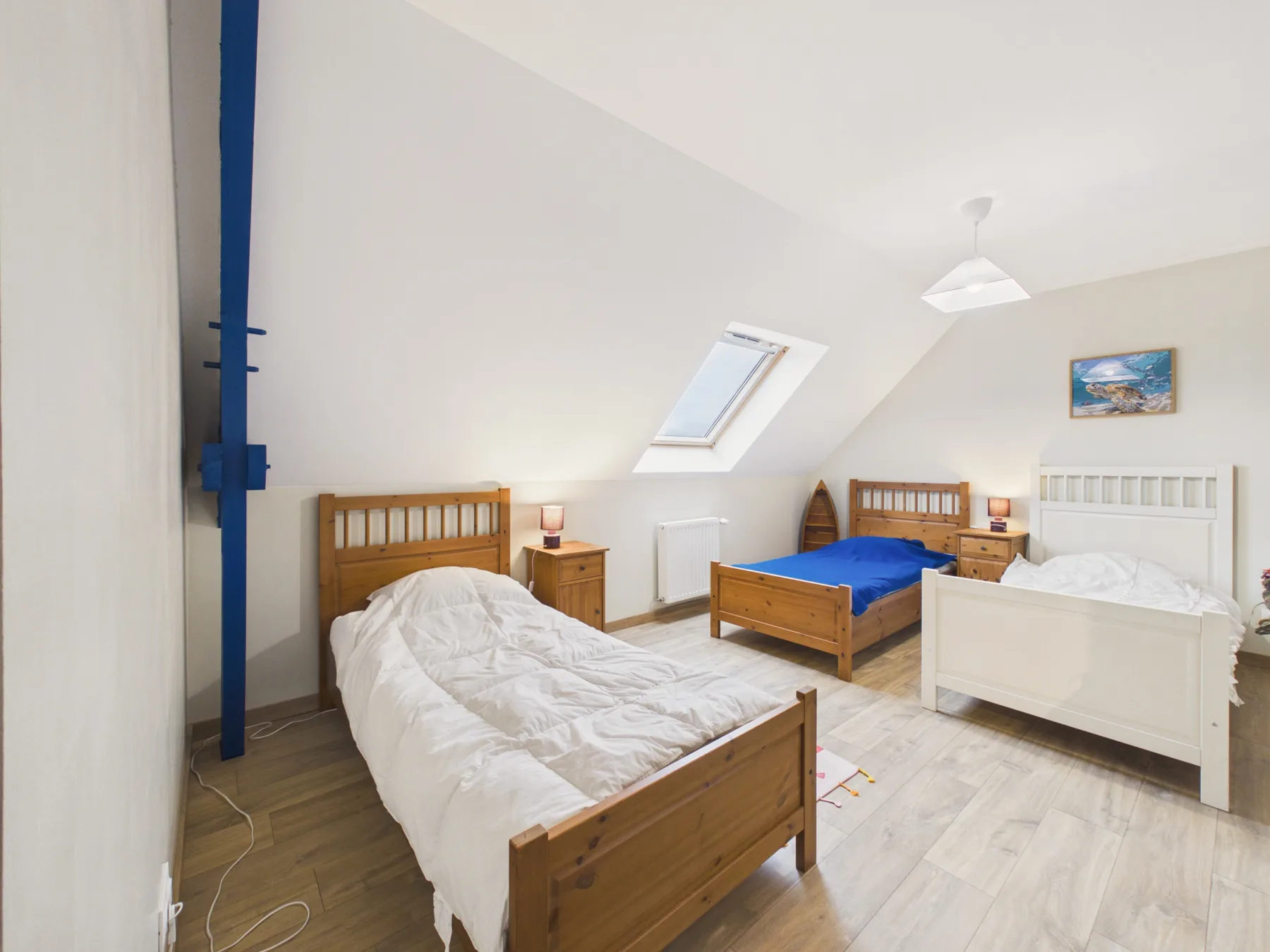 A bright attic bedroom with several beds and a skylight.