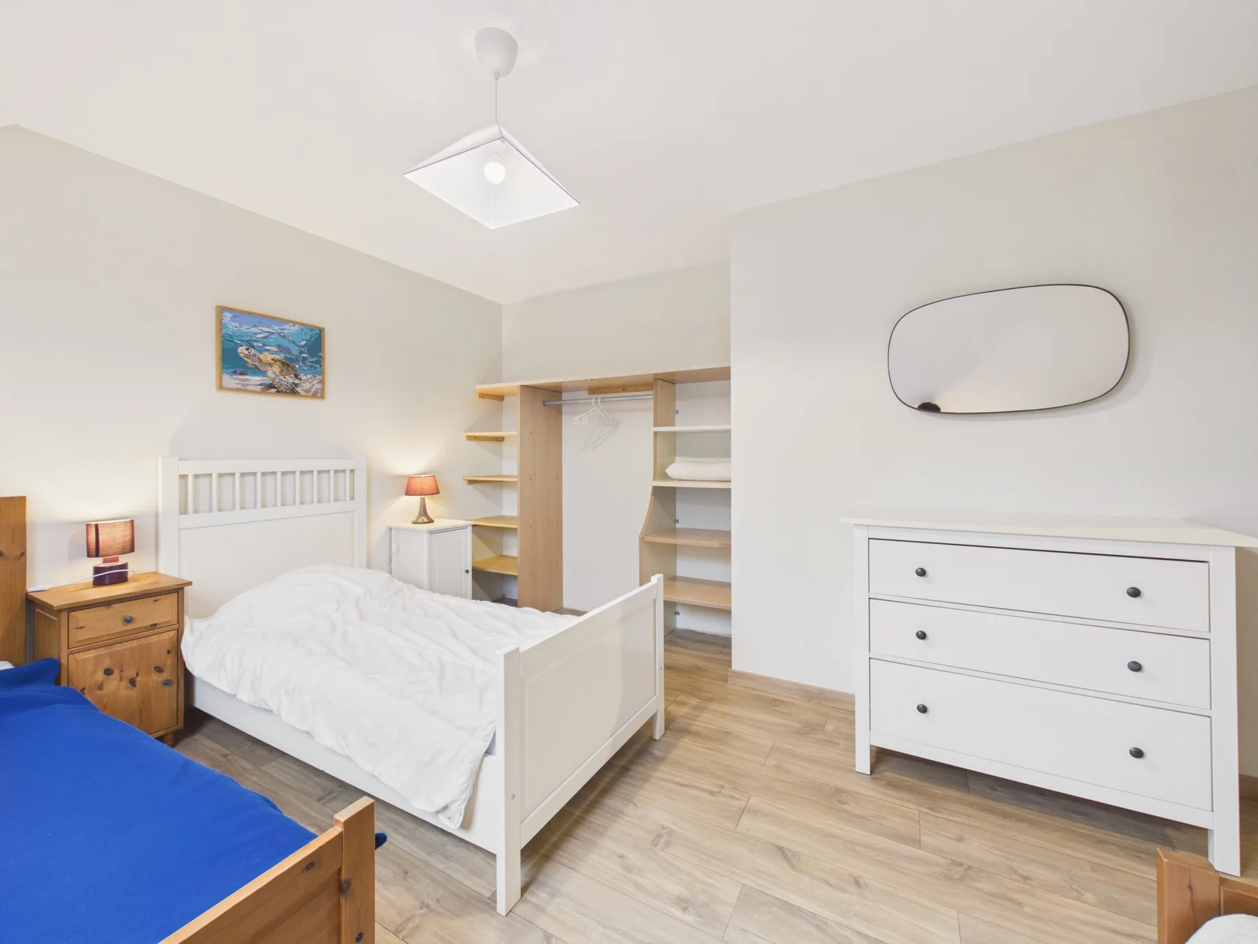 A bright bedroom with two beds and a dresser.