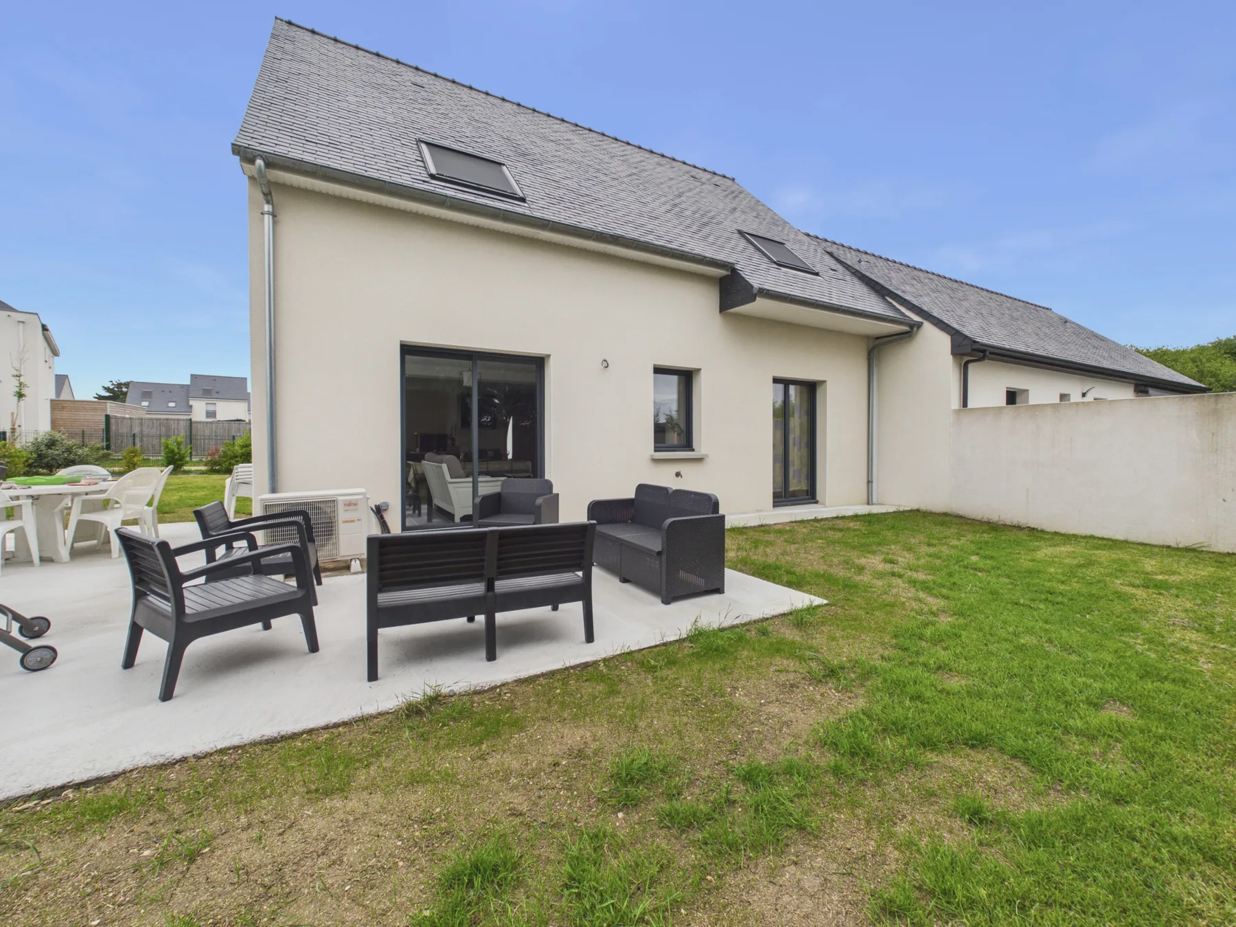 A house exterior with a patio seating area and lawn.