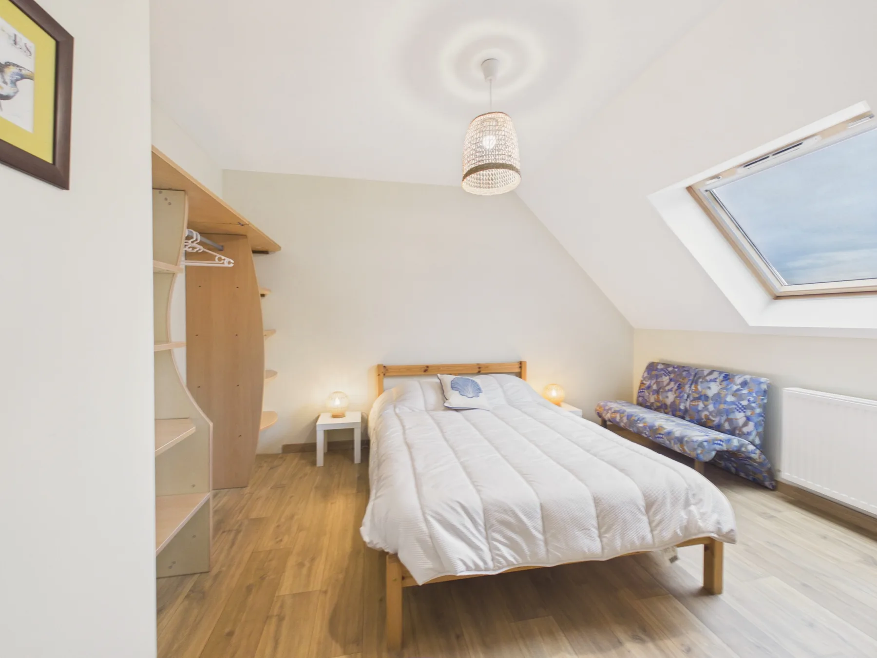 A bright bedroom with a double bed and a sloped skylight.