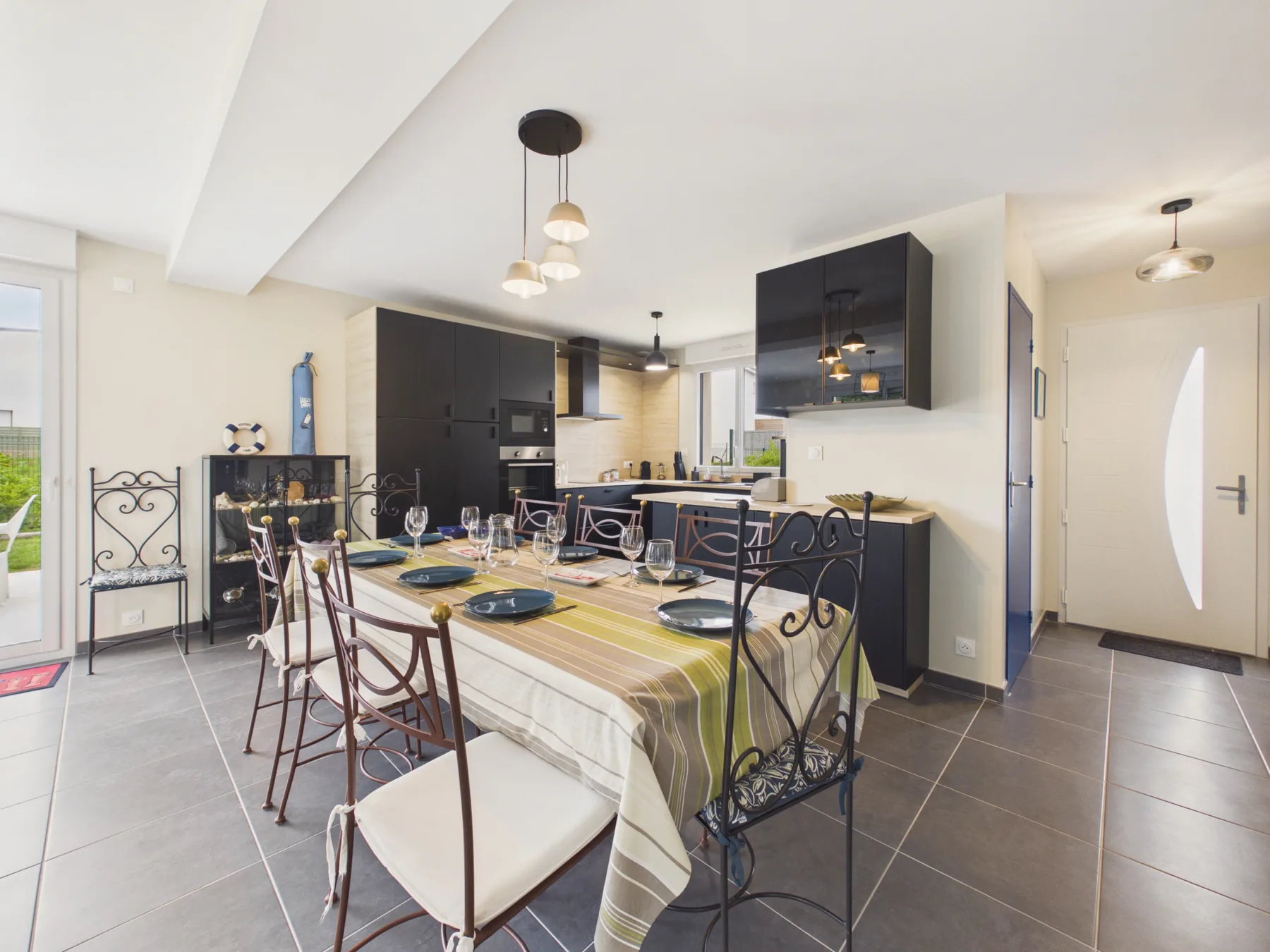 A dining area with a table set in front of a modern kitchen.