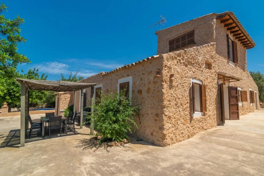 A stone house with a shaded outdoor dining area beside it.