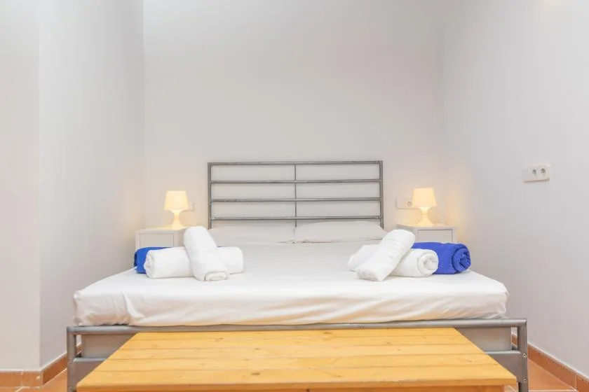 A bedroom with a neatly made bed and a wooden table in front.