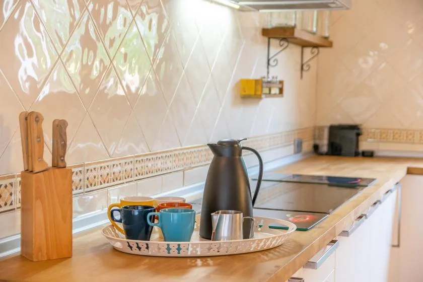 A kitchen counter with a tray of cups and a thermos beside the cooktop.