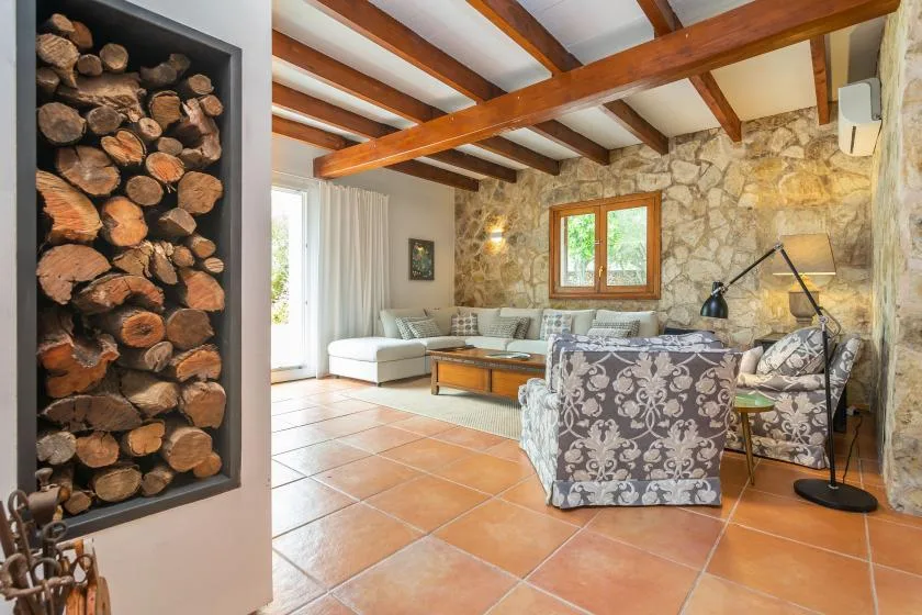 A living room with stone walls, exposed wooden beams, and seating.