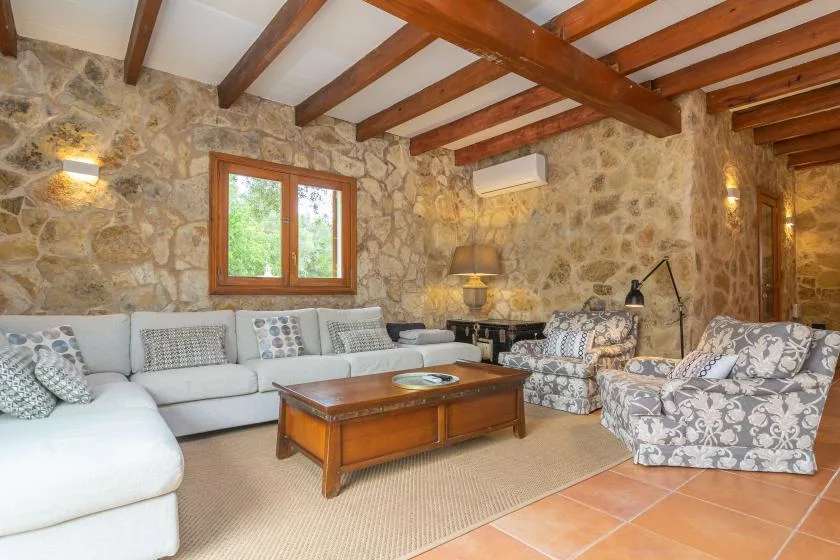 A rustic living room with stone walls, seating, and a wooden coffee table.