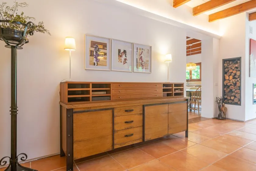 A bright living area features a long wooden cabinet beneath framed artwork.