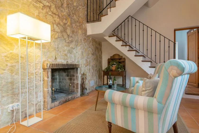 A sitting area with striped seating beside a stone fireplace and staircase.