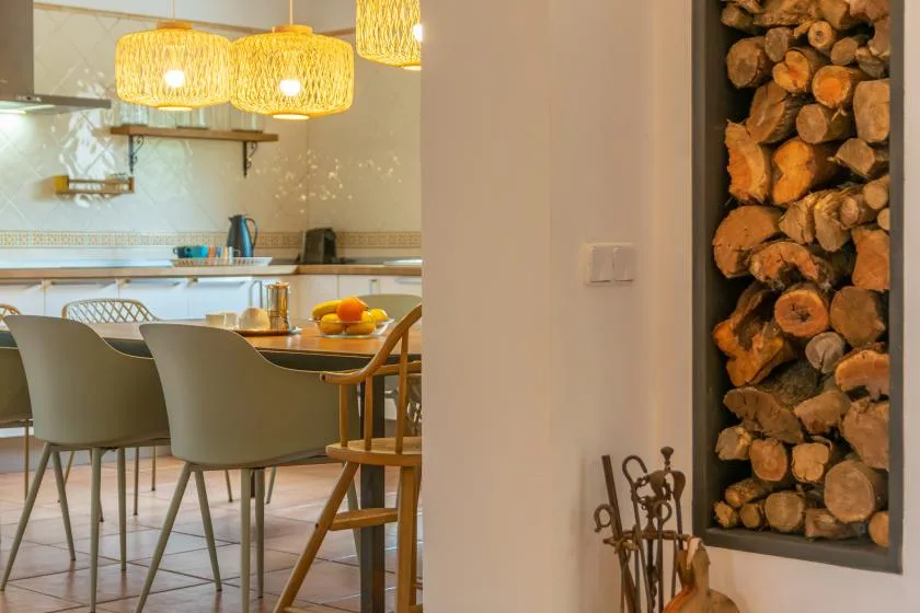 A dining area beside a kitchen, with pendant lights above the table.