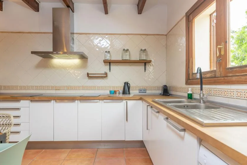 A bright kitchen with white cabinetry, wooden countertops, and a window.