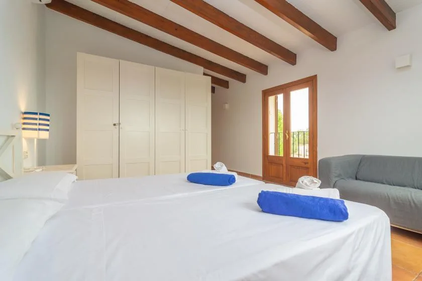 A bedroom with a large bed, white wardrobes, and a wooden balcony door.