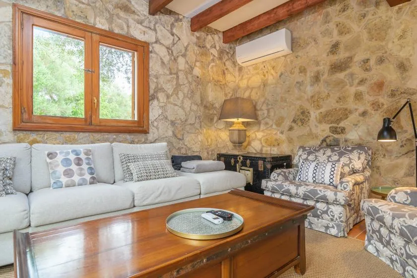 A stone-walled living room with seating around a wooden coffee table.