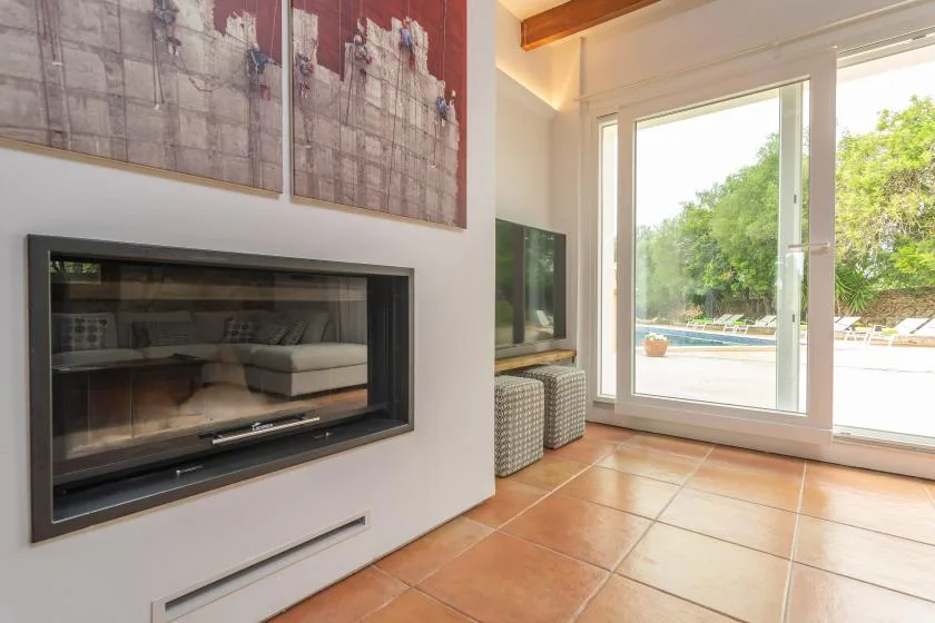 A bright living room has a built-in fireplace beside large glass doors opening onto a patio.