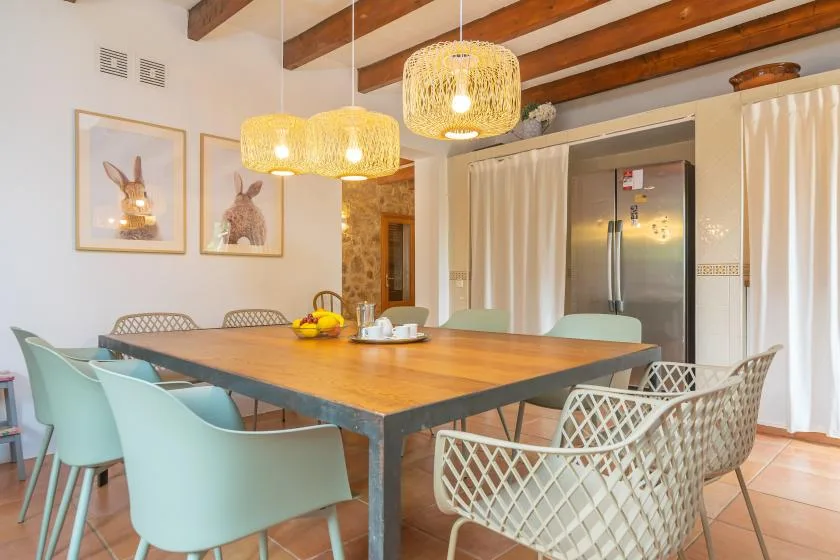 A dining area with a large wooden table, assorted seating, and woven pendant lights.