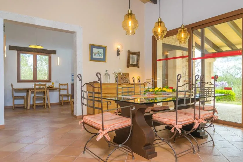 Comedor con una mesa larga y asientos junto a grandes puertas de vidrio.