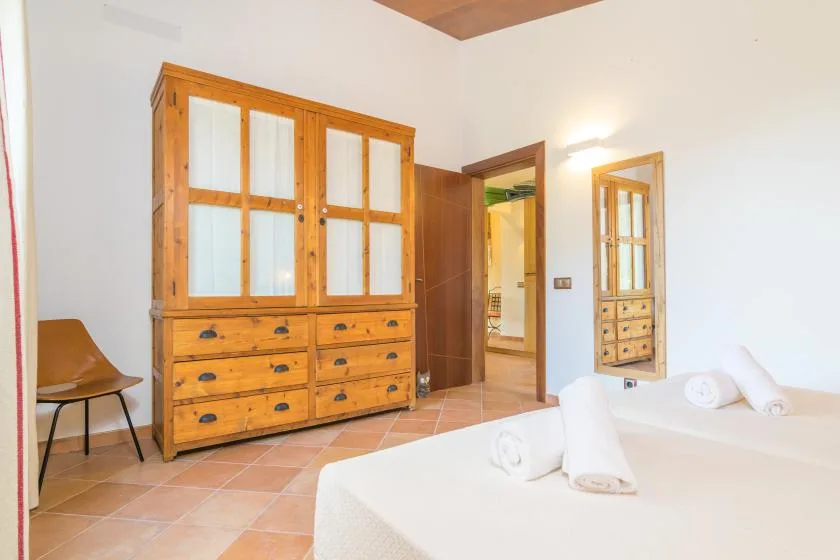 Un dormitorio con una cama, un armario de madera y una silla.