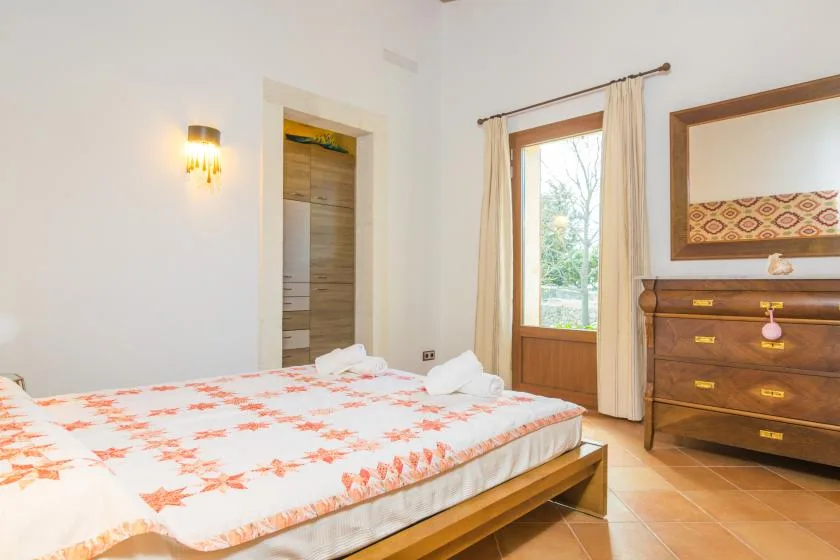 Un dormitorio con una cama grande, una ventana y una cómoda de madera.