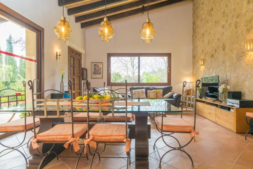 Un comedor con una mesa larga y sillas, junto a una zona de estar con sofá.