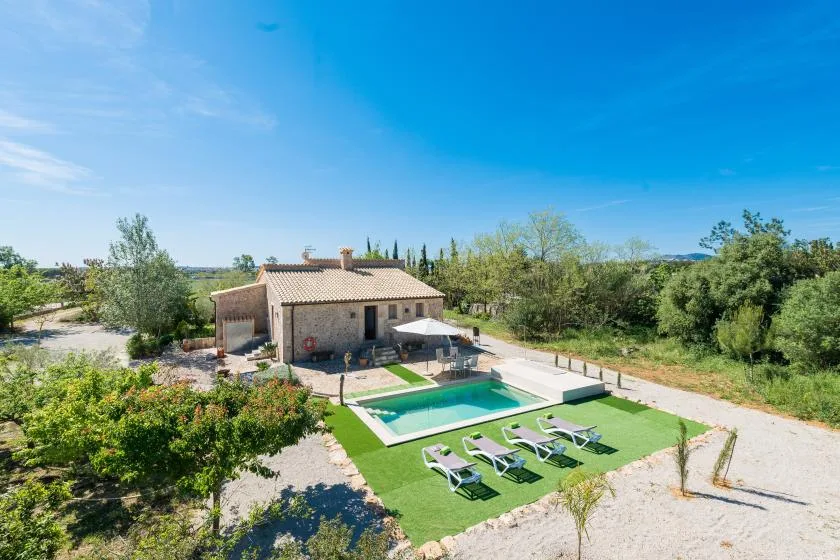 Una casa pequeña junto a una piscina y una zona de estar al aire libre.
