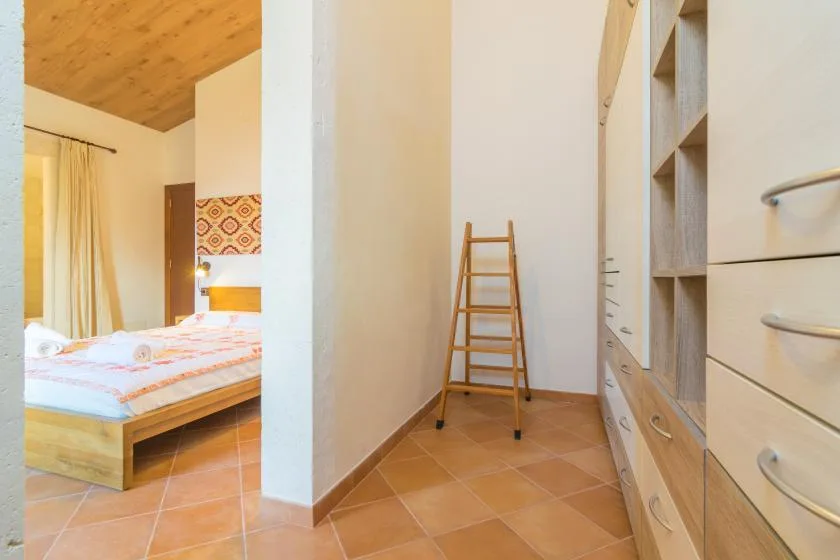 Un dormitorio da a una estrecha zona de vestidor con almacenamiento integrado y una escalera.
