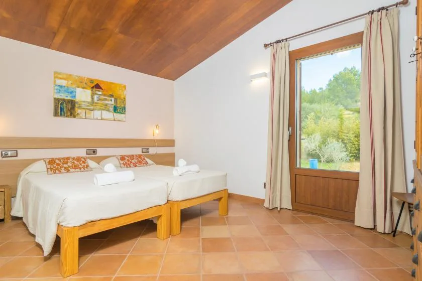 Un dormitorio con dos camas junto a una ventana grande con vistas a la vegetación.