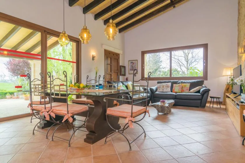 Sala de estar y comedor con mesa, asientos y ventanales.