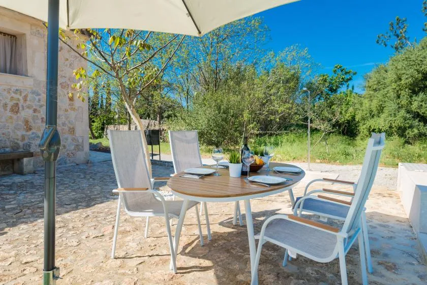 Una zona de comedor al aire libre con una mesa redonda y asientos bajo una sombrilla grande.