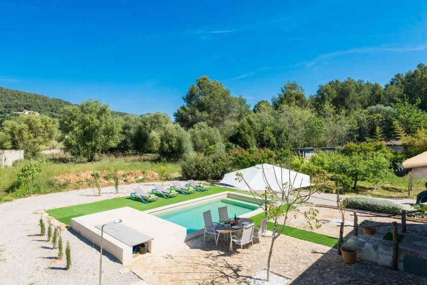 Una piscina al aire libre está en una zona ajardinada rodeada de árboles.