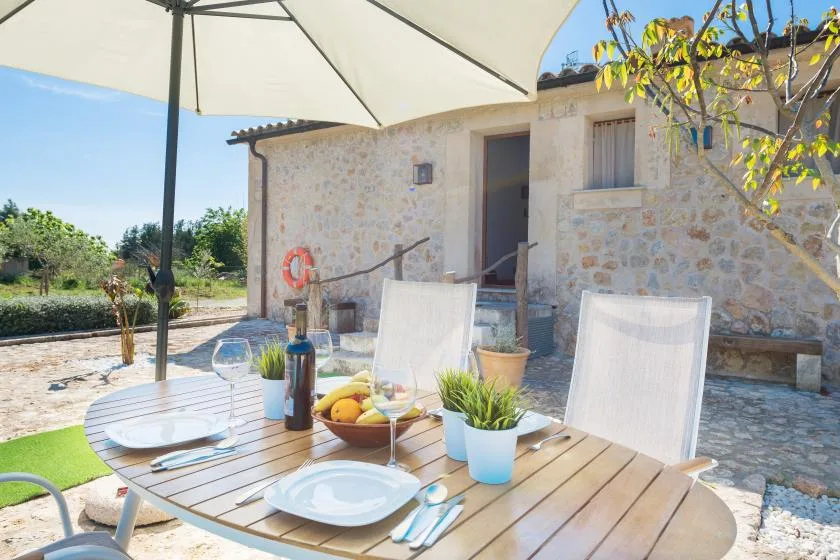 Una zona de comedor al aire libre con la mesa puesta junto a un edificio de piedra.