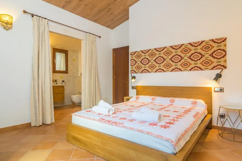 Un dormitorio con cama de madera, ropa de cama estampada y una puerta abierta al baño.